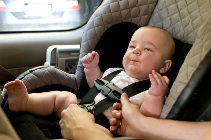 Baby in a back seat located child safety seat